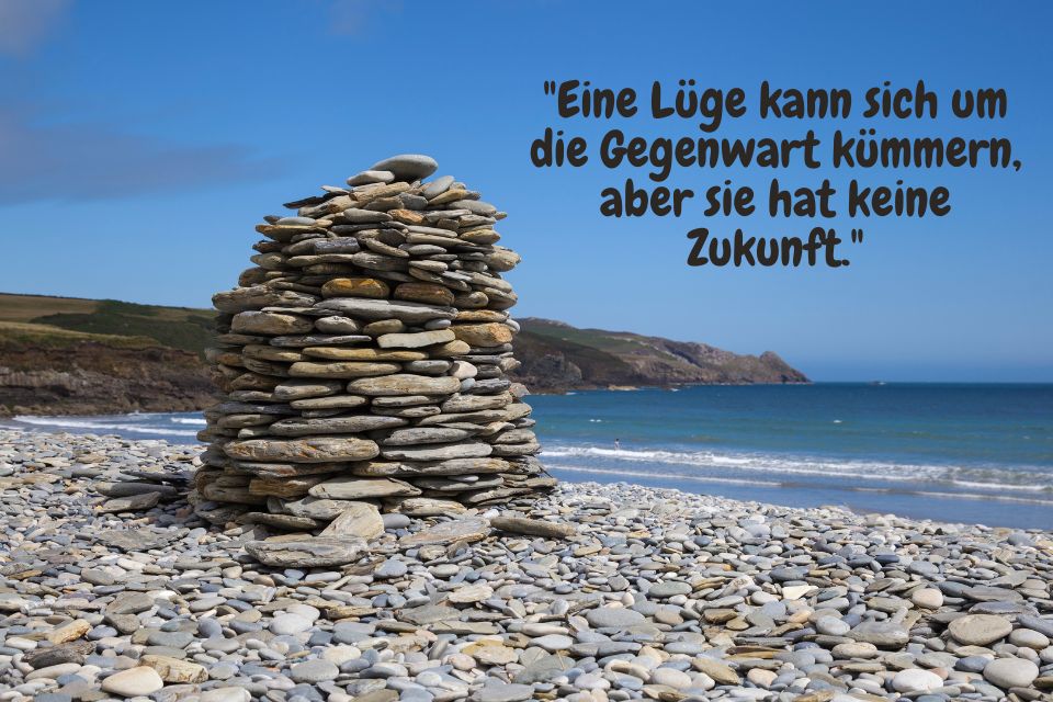 Aufgestapelte Steine an der steinigen Bucht und Spruch: "Eine Lüge kann sich um die Gegenwart kümmern, aber sie hat keine Zukunft."