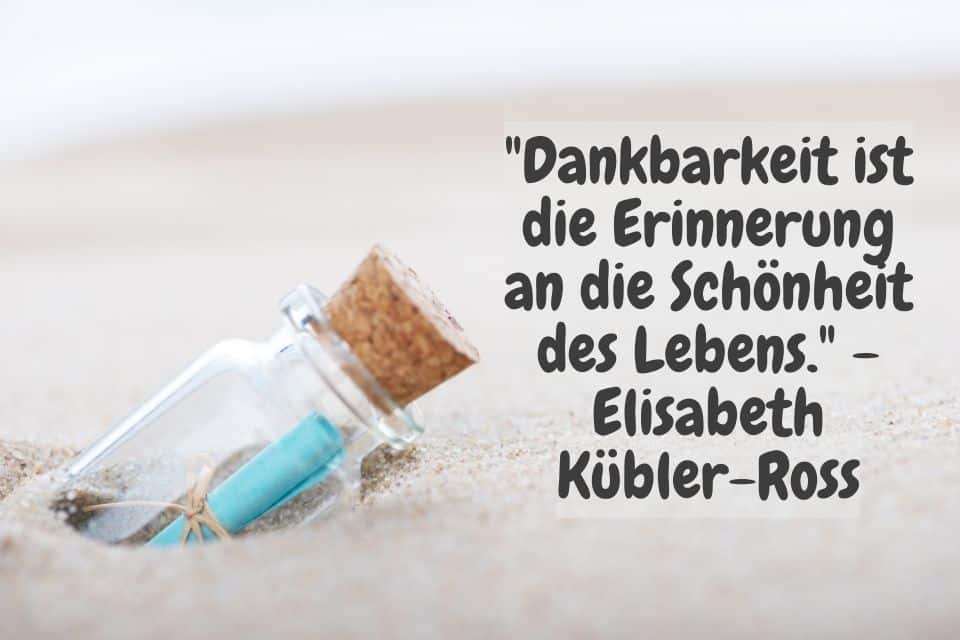 Im Sand steckende Flaschenpost mit Zitat: "Dankbarkeit ist die Erinnerung an die Schönheit des Lebens." - Elisabeth Kübler-Ross