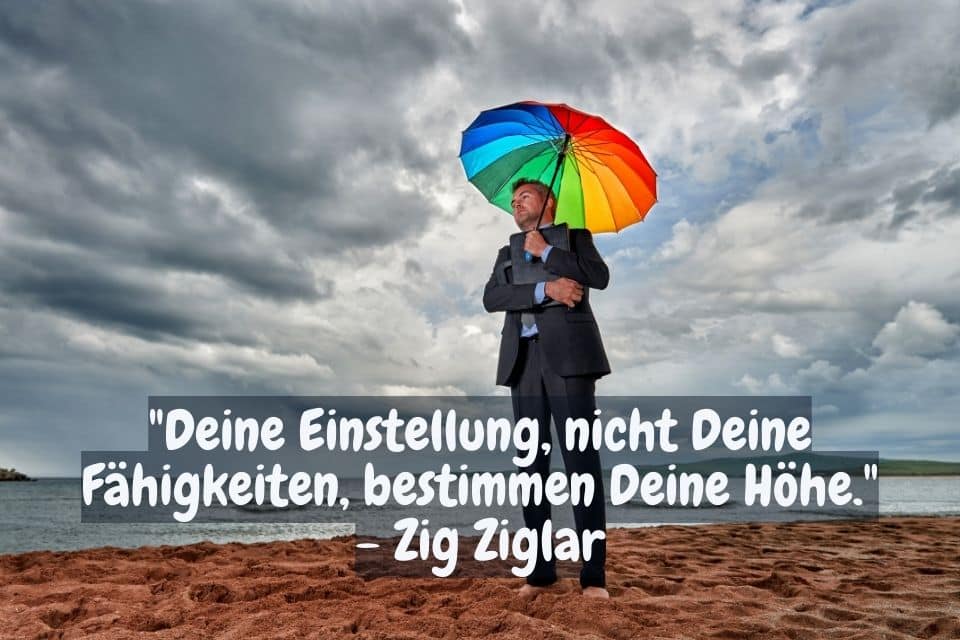 Mann mit buntem Schirm. Zitat: "Deine Einstellung, nicht Deine Fähigkeiten, bestimmen Deine Höhe." - Zig Ziglar