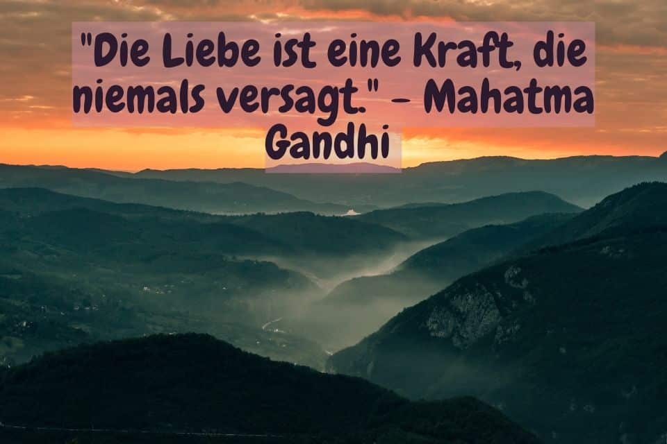 Blick über eine Bergkette im Abendrot und Spruch: "Die Liebe ist eine Kraft, die niemals versagt." - Mahatma Gandhi