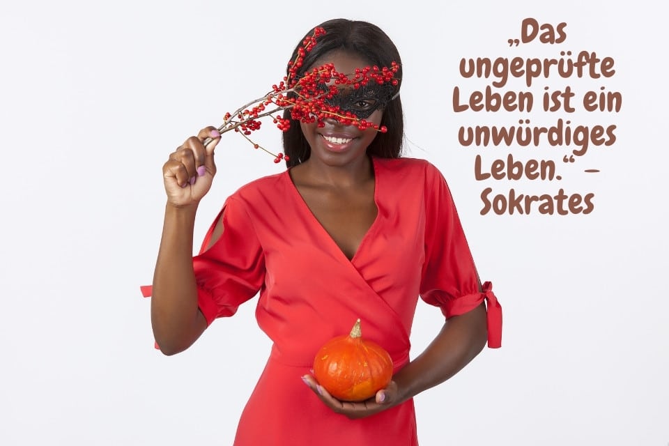Giovane donna nera vestita di rosso con una zucca arancione e una perenne rossa - "La vita non esaminata è una vita indegna." - SocratesKnow Yourself