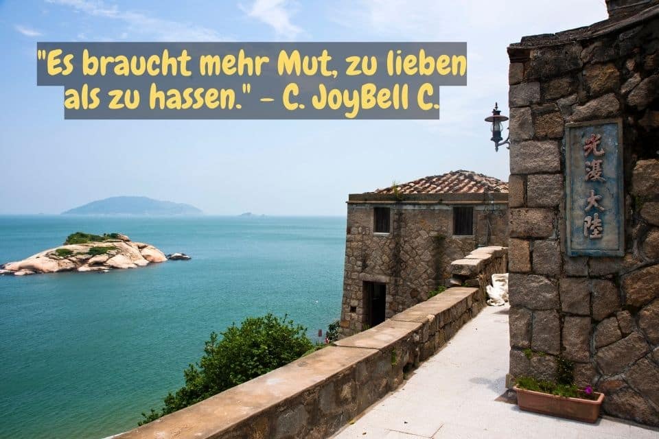 Blick auf das blaue Meer und Spruch: "Es braucht mehr Mut, zu lieben als zu hassen." - C. JoyBell C.