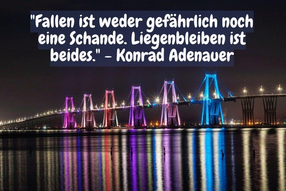 Farbig beleuchtete Brücke über einen Fluss mit Zitat: "Fallen ist weder gefährlich noch eine Schande. Liegenbleiben ist beides." - Konrad Adenauer