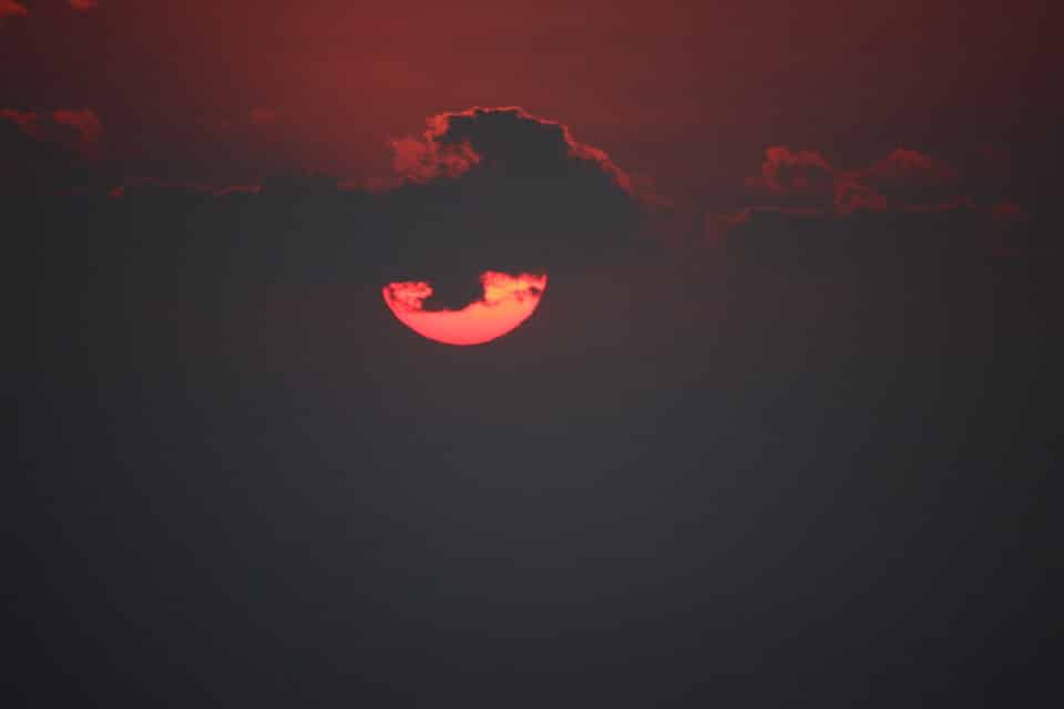 Sonnenuntergang rote Sonne hinter Wolke