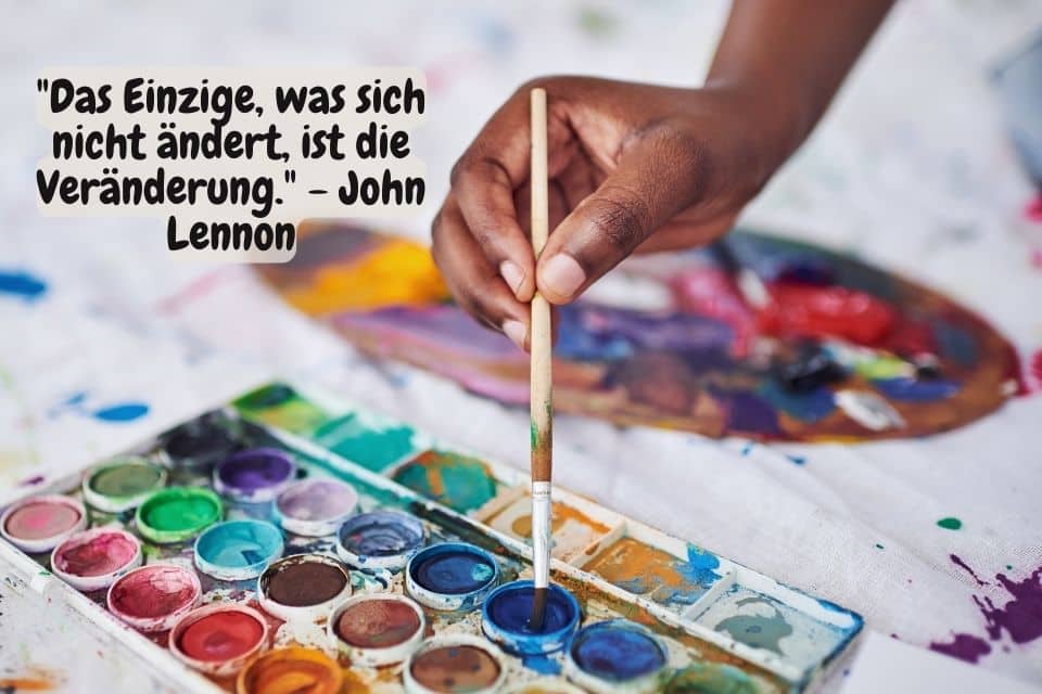 Hand mit Pinsel in Wasserfarben und Zitat: "Das Einzige, was sich nicht ändert, ist die Veränderung." - John Lennon