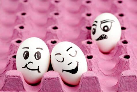Drei Eier in einer pinkfarbenen Aufbewahrungsschachtel, auf den Eier sind verschiedene Emojis aufgezeichnet