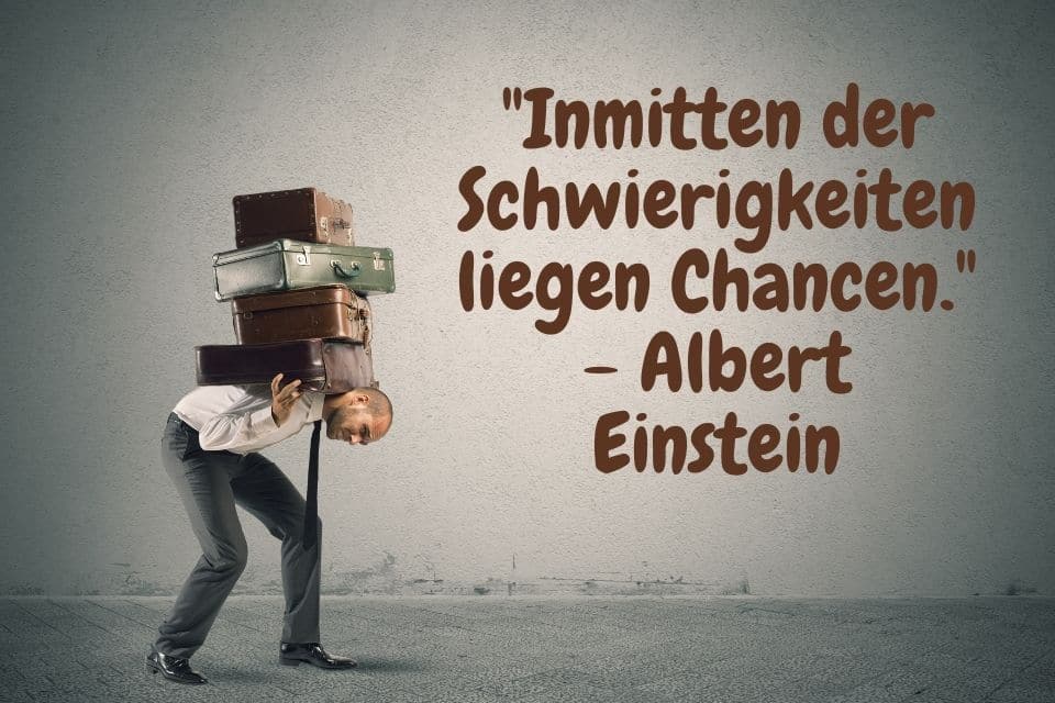 Ein Mann schleppt viele Koffer mit Spruch: "Inmitten der Schwierigkeiten liegen Chancen." - Albert Einstein