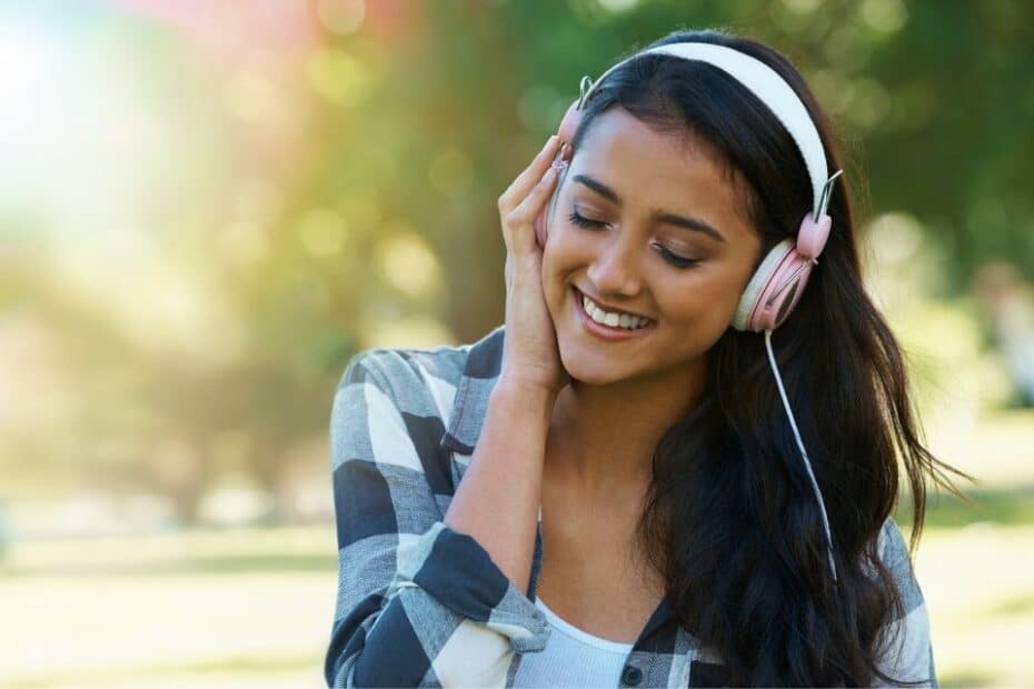 A young woman listens to music with headphones from: With Phil Collins - Love Songs & Ballad let go