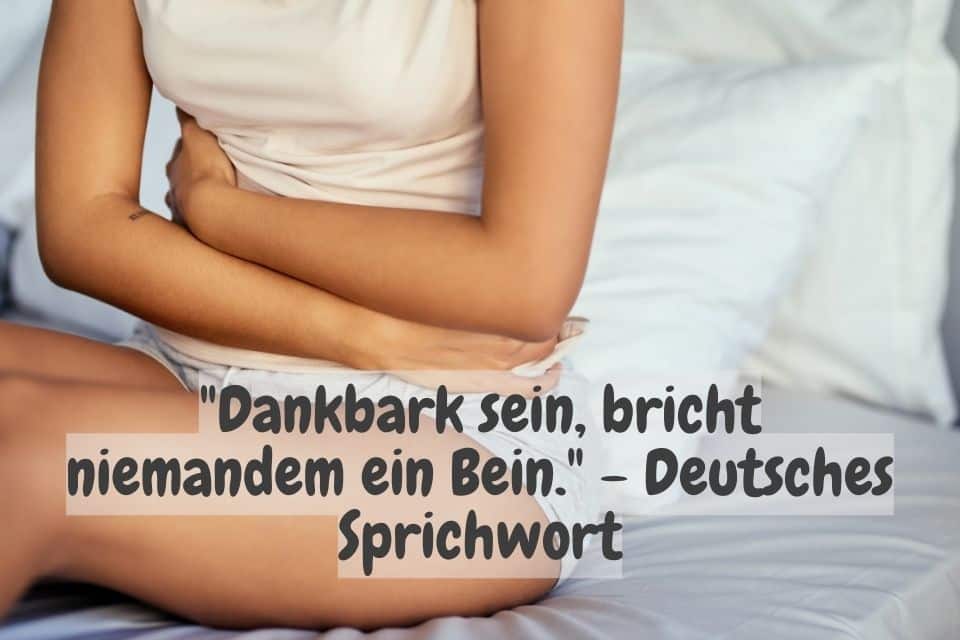 Frau sitzt im Bett und macht sich zu folgendem Zitat Gedanken: "Dankbark sein, bricht niemandem ein Bein." - Deutsches Sprichwort