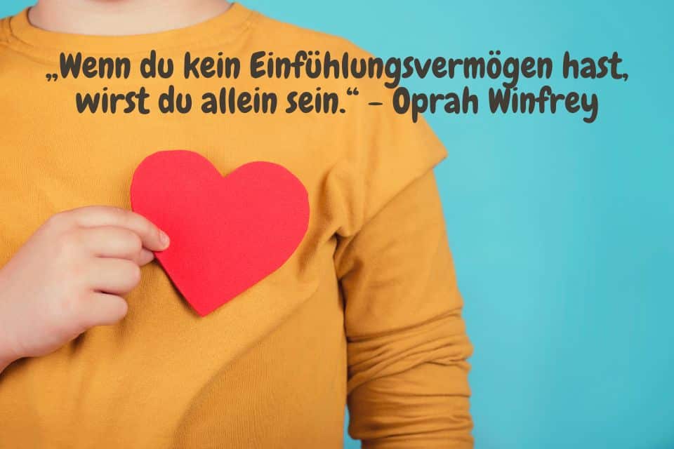 Mann mit gelben Pullover hält sich ein rotes Herz über sein Herz mit Zitat: „Wenn du kein Einfühlungsvermögen hast, wirst du allein sein.“ - Oprah Winfrey