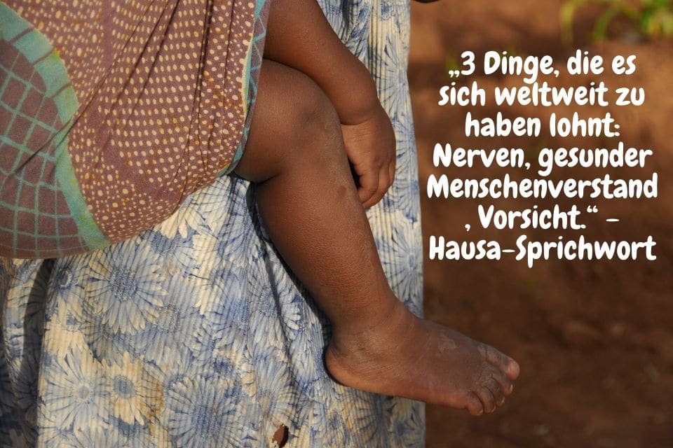 Frau mit Baby im Hugepack und Zitat: tolle afrikanische Sprichwörter„3 Dinge, die es sich weltweit zu haben lohnt: Nerven, gesunder Menschenverstand, Vorsicht.“ - Hausa-Sprichwort
